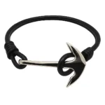 Brazalete náutico negro con cordón de cuero y ancla metálica plateada como cierre.