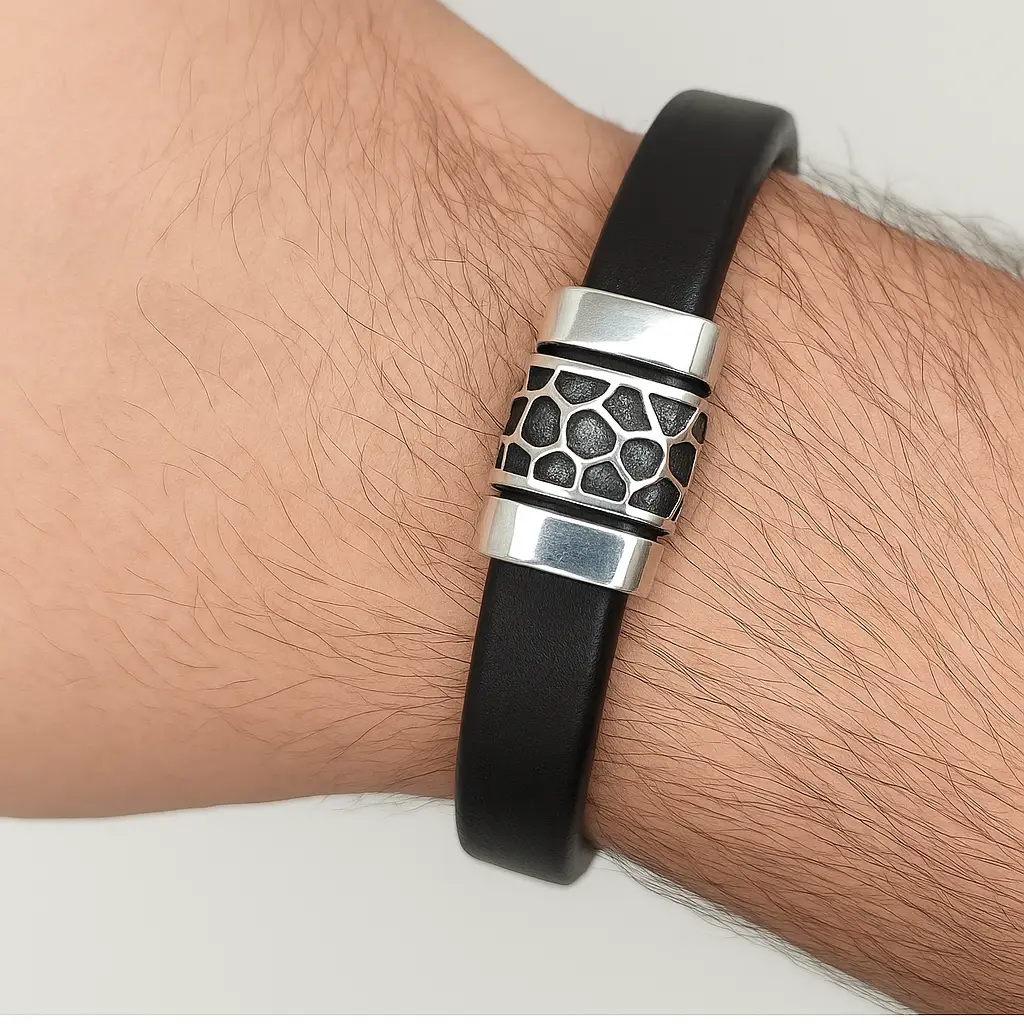 Brazalete de Piel Nórdico con Detalle de Acero. "Brazalete de banda de piel negra gruesa con cierre y adorno cilíndrico de acero pulido y texturizado."