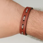 Brazalete de piel negro con remaches o herrajes de acero en forma de media luna.