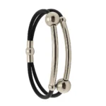 "Brazalete de Piel y Acero, formado por cuero negro y dos tubos curvos de metal pulido."