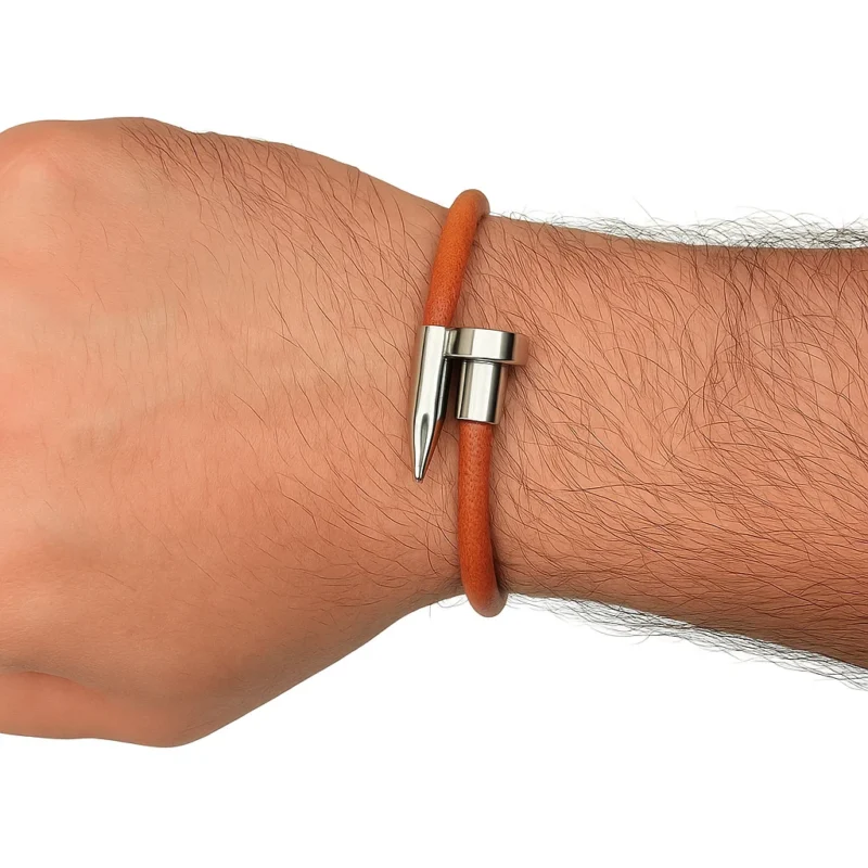 Una pulsera de cuero liso de color marrón anaranjado con un cierre y detalles de metal plateado en forma de clavo, sobre un fondo blanco.