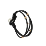 "Primer plano de pulsera de cuero anudado con múltiples bolitas de metal que decoran las tiras."