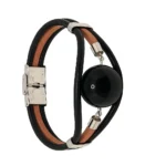 "Brazalete con Bola de , montado sobre tiras de cuero y cierre de seguridad."