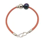 Brazalete de piel trenzada gruesa con pieza central de acero labrado y cierre magnético.